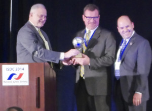 MC Michael Simpson (left) presents the award to Mike Laidley (center) and Frank DeMauro
